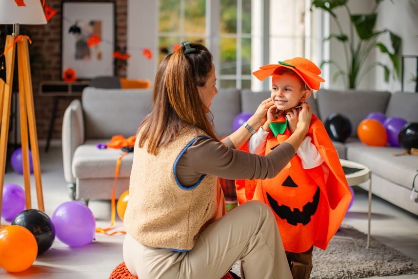 Mother helping kid in halloween costume