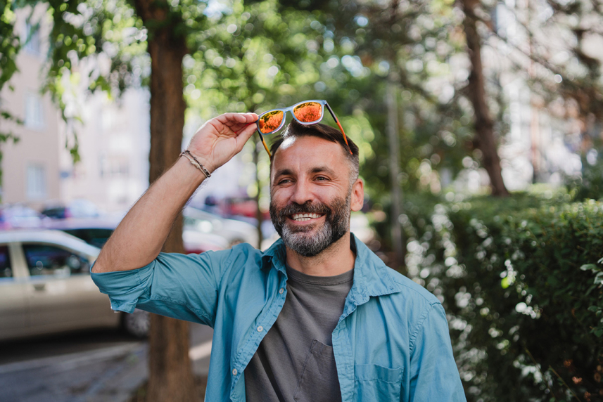Man walking outside while holding sunglasses