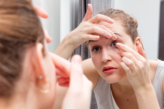 Young adult woman thinking about the difference between her eyeglasses and contact lens prescriptions 