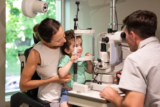Kid sitting on his mothers lap getting an eye exam
