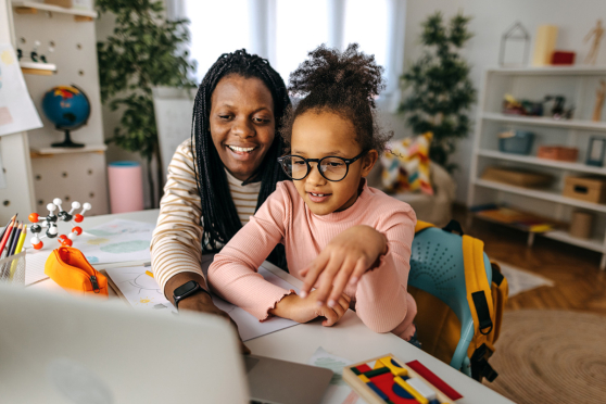 Mother helping daughter use the laptop
